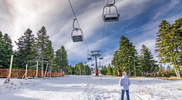 Stok narciarski z wyciągiem na tle nieba i lasu zimą, idealne miejsce do sportów zimowych.